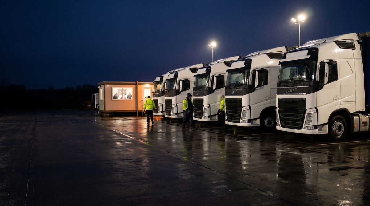 A row of lorries parked under floodlights in a haulage depot at night