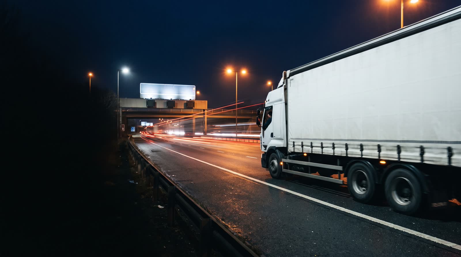 A curtainsider articulated lorry on a British motorway at night